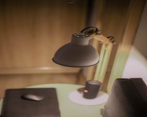 Close up of a notebook computer on a wooden desk with a small lamp beside it providing comfortable illumination
